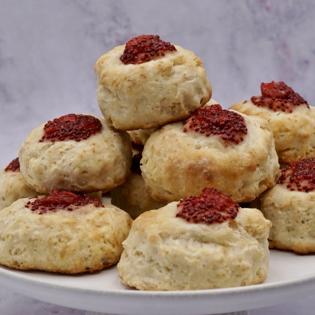 A pile of jam scones on a plate. 