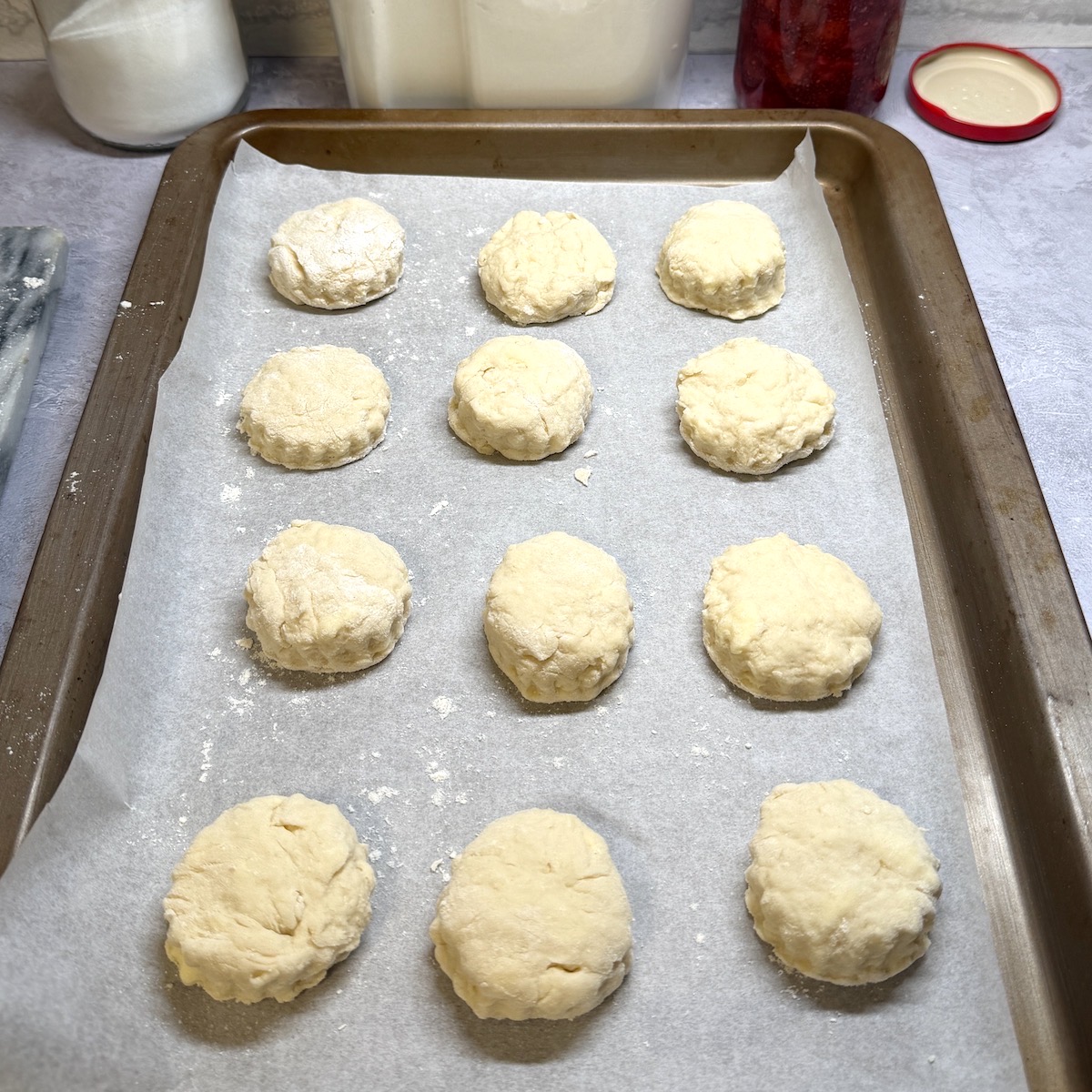 Twelve unbaked scones on a baking tray.