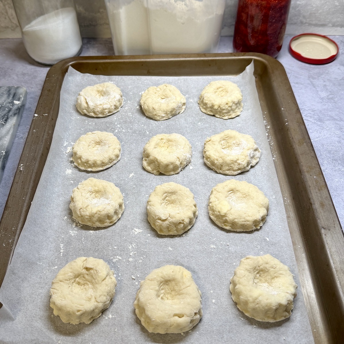 Twelve unbaked scones on a baking tray.