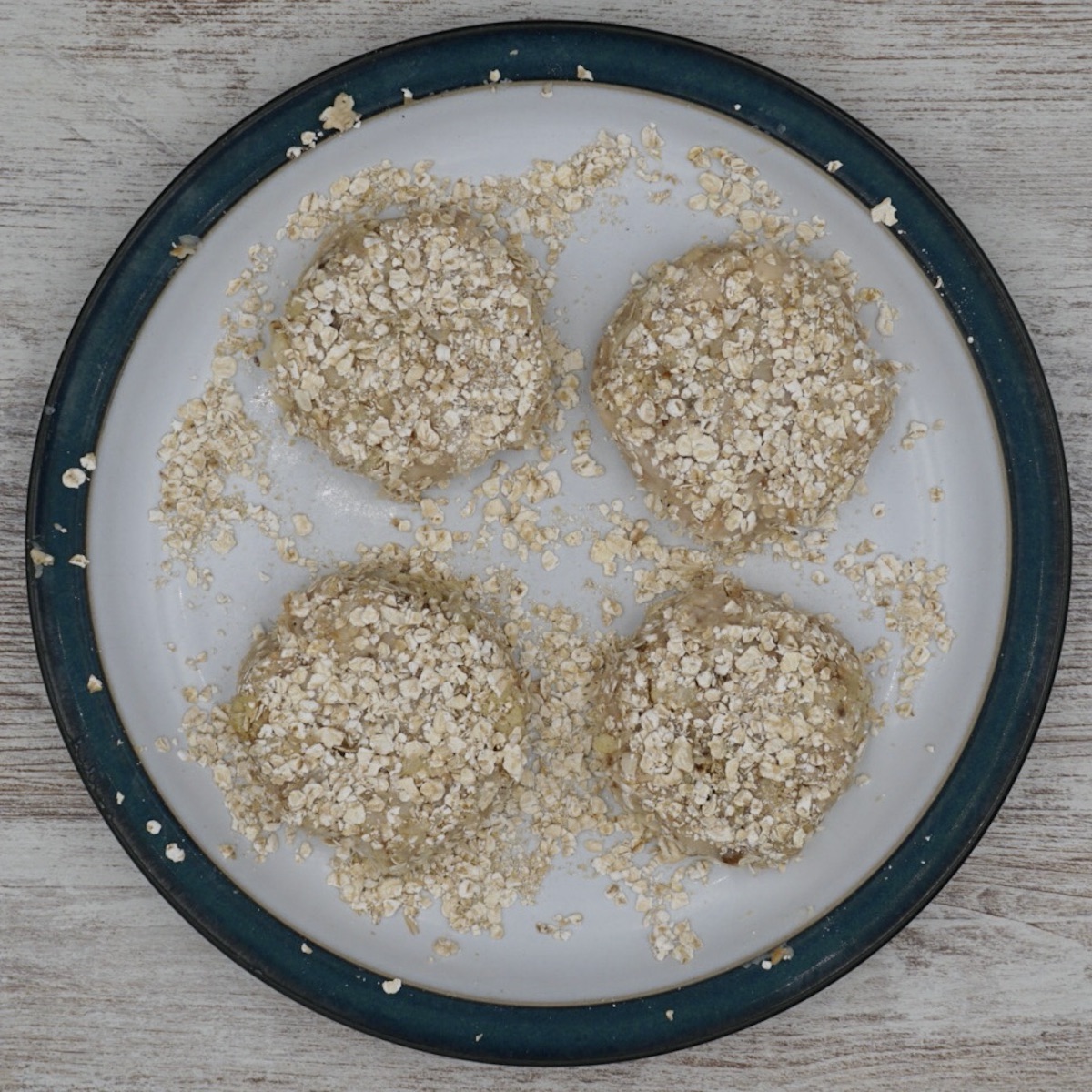 Four uncooked cauliflower cakes on a plate.