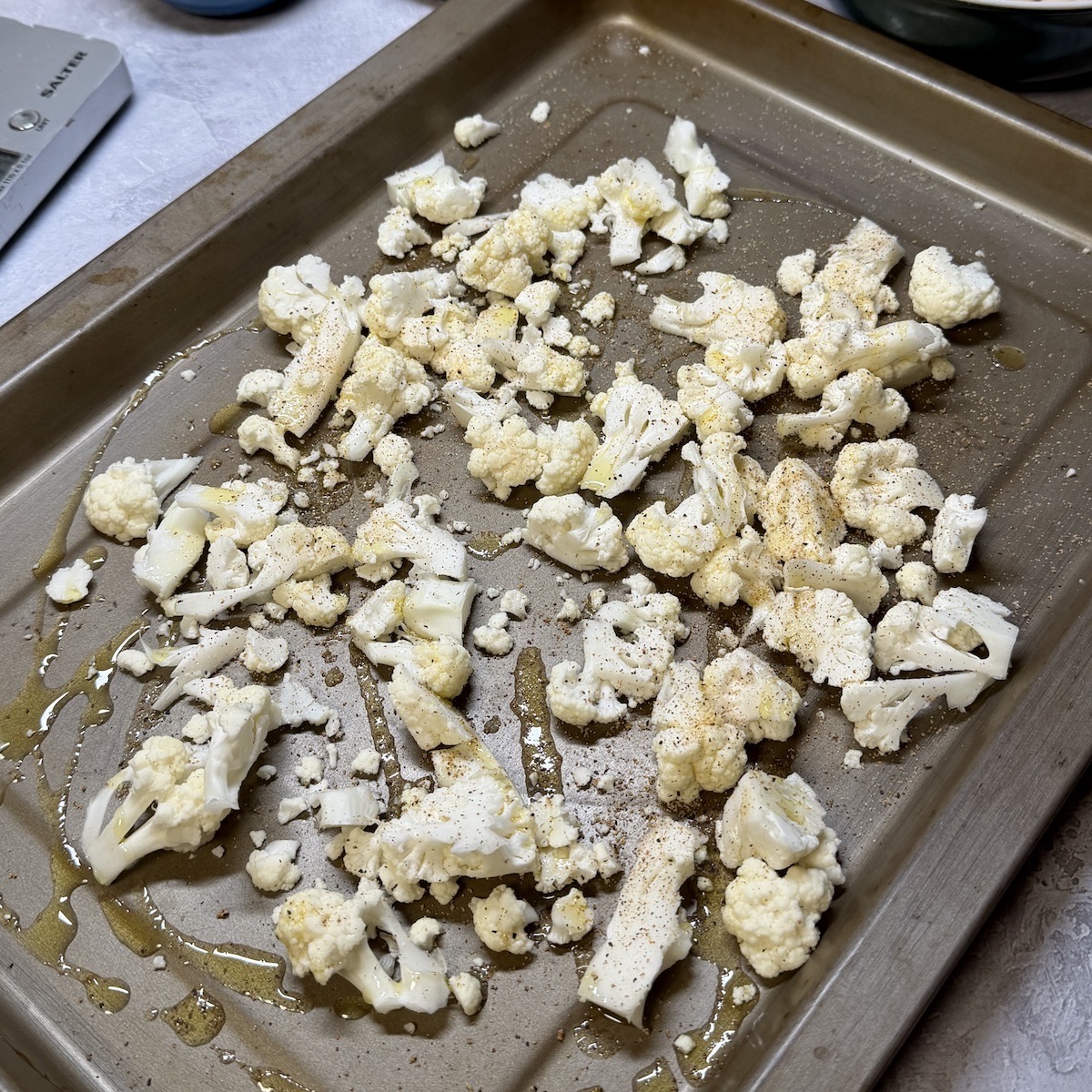 Chopped cauliflower on a baking tray drizzled with oil.