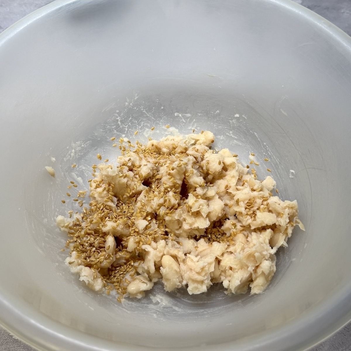 Mashed white beans and flax seeds in a bowl.