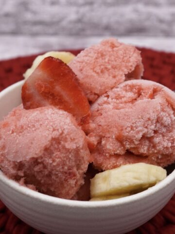 A bowl of strawberry banana sorbet with fruit.
