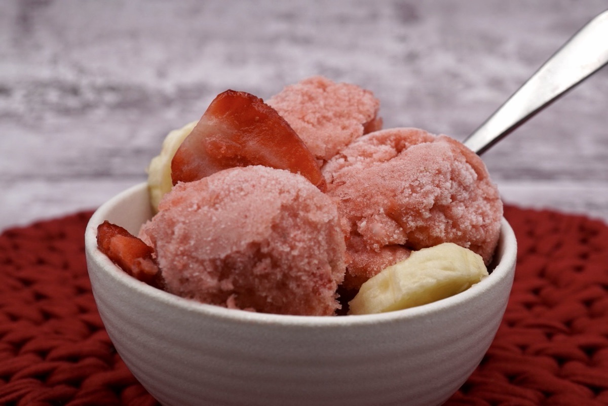 A bowl of strawberry banana ice cream with fruit.