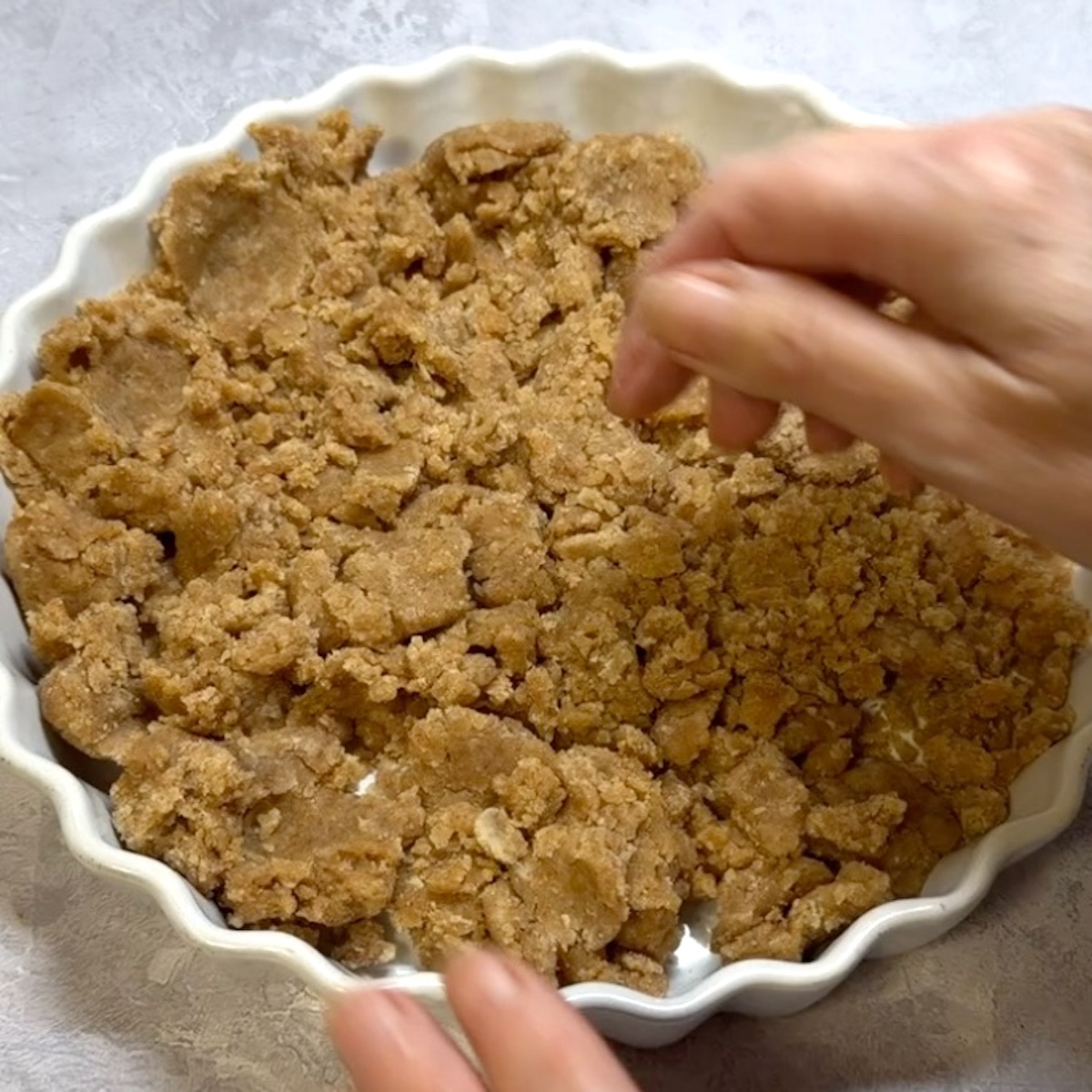 A quiche dish being lined with olive oil pastry dough.