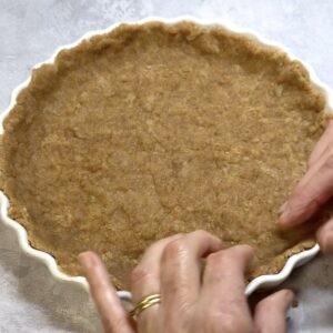 Olive oil pastry being pressed into a quiche dish.
