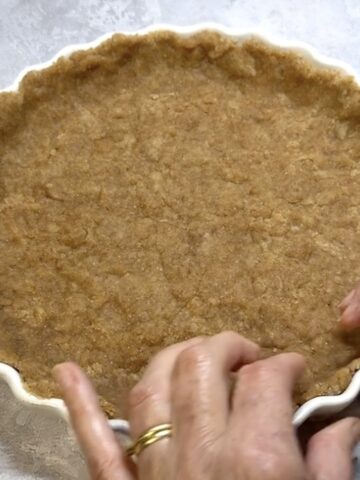 Olive oil pastry being pressed into a quiche dish.