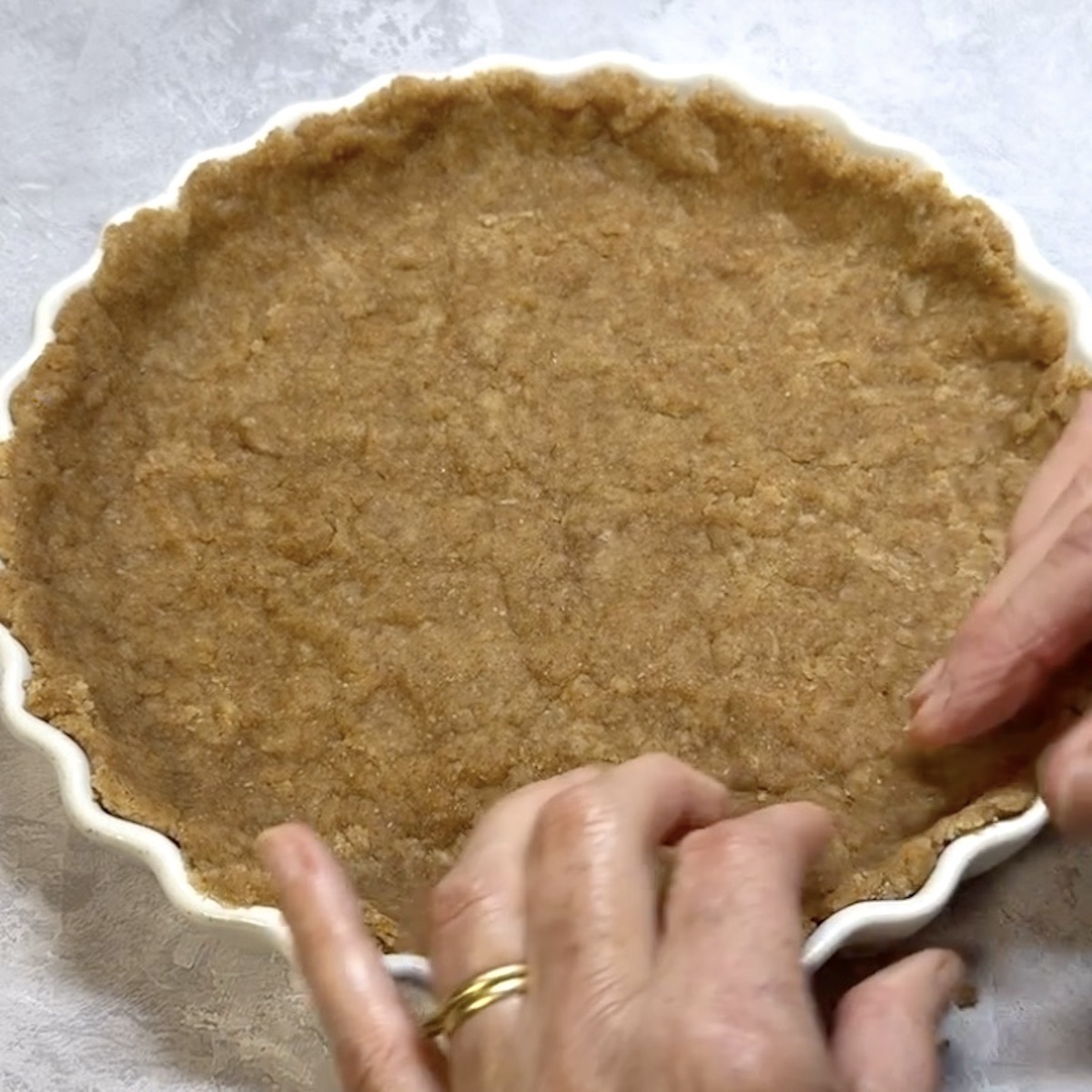 Olive oil pastry being pressed into a quiche dish.