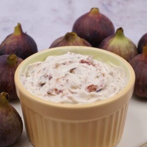 A bowl of fig mousse next to some figs.