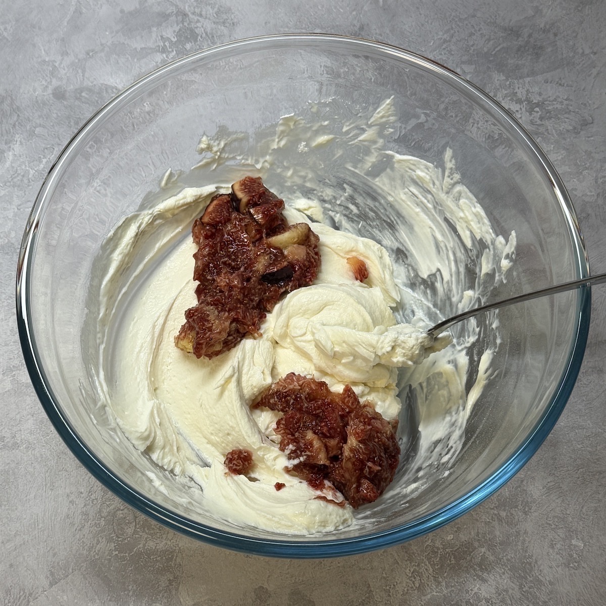 Mashed figs added to a bowl of mousse.